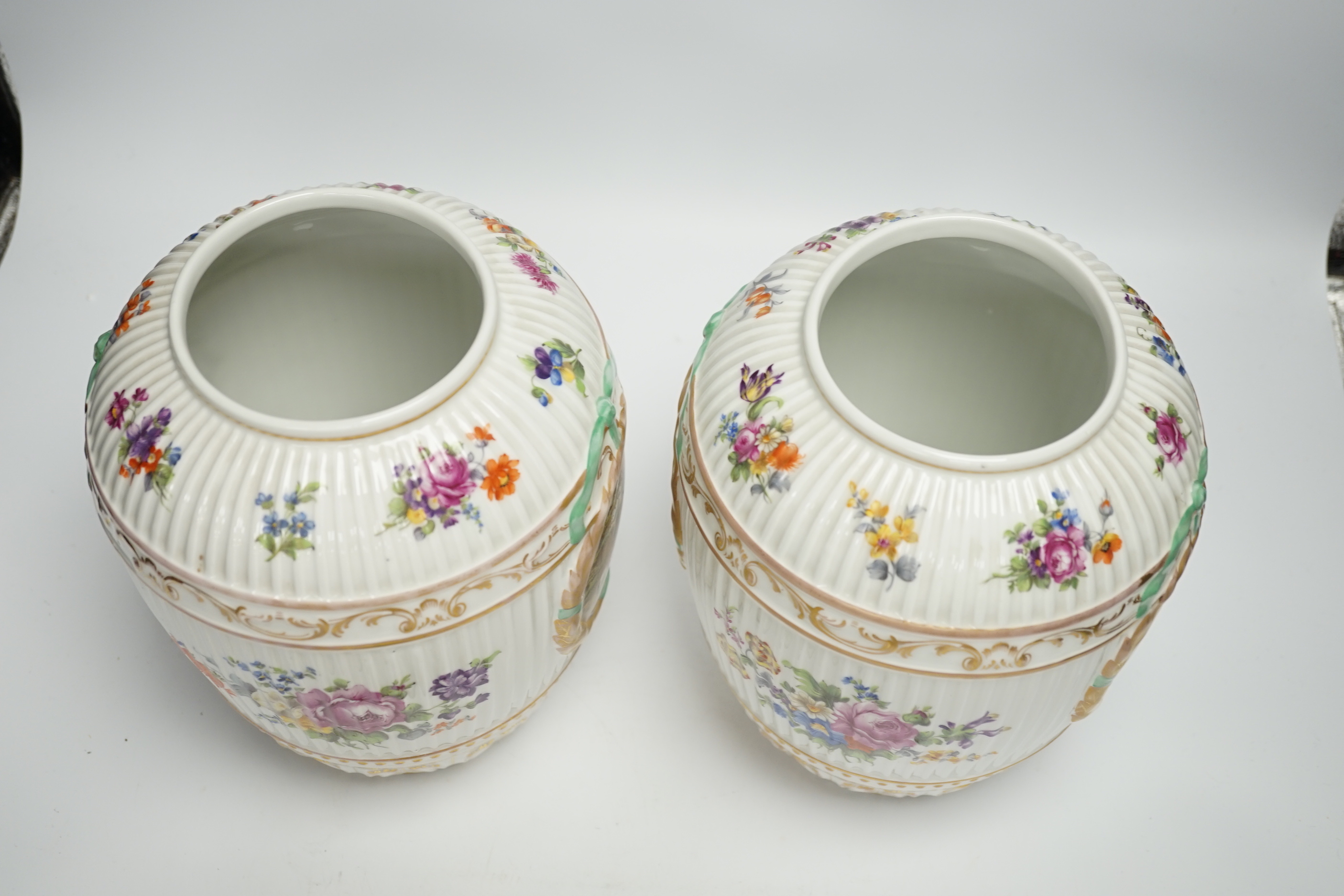 A pair of Continental floral decorated ribbed jars and covers with figural cartouches, 32cm high